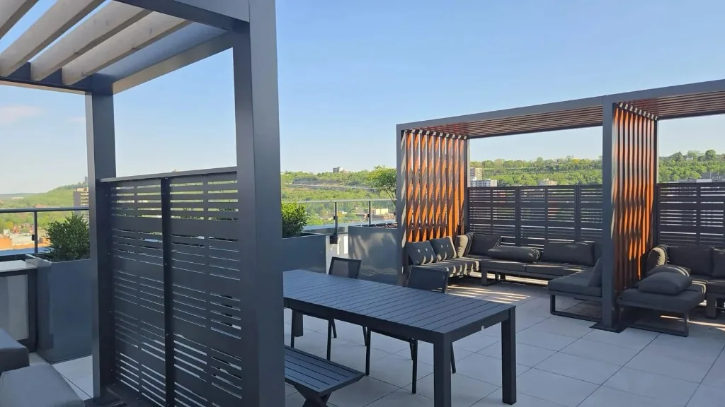 Rooftop terrace with outdoor dining table and lounge seating under pergolas overlooking the valley